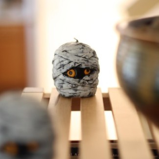 A cute mummy head candle sits on a shelf.